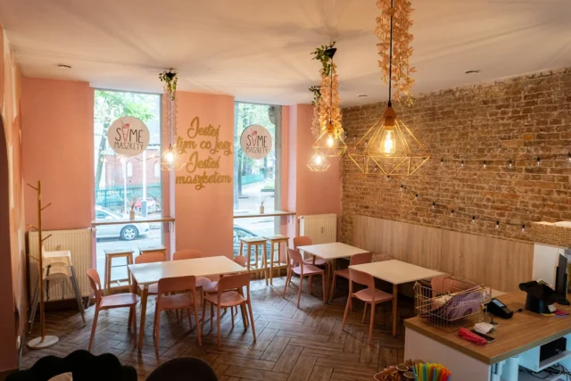Sala z ceglaną ścianą i różowymi stolikami w Same Maszkety